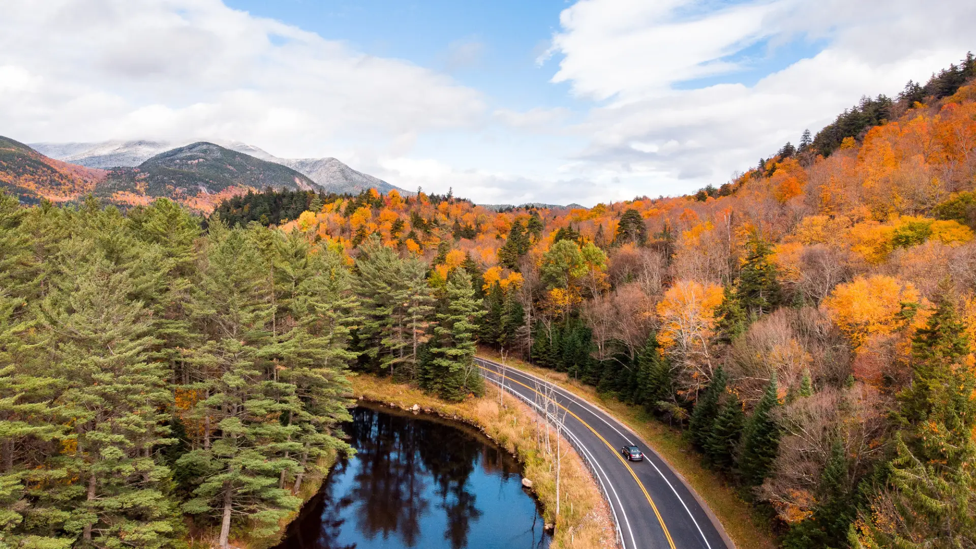 A winding road near a river with fall scenery.