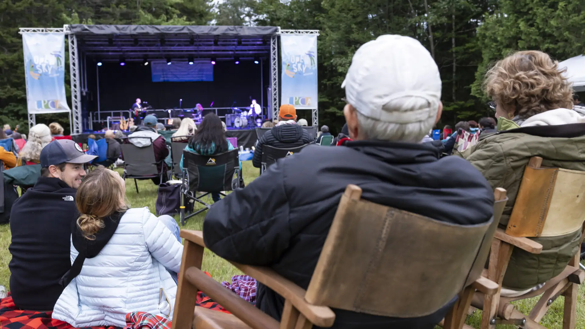 People sit in lawn chairs in the grass at Open Sky Music Festival