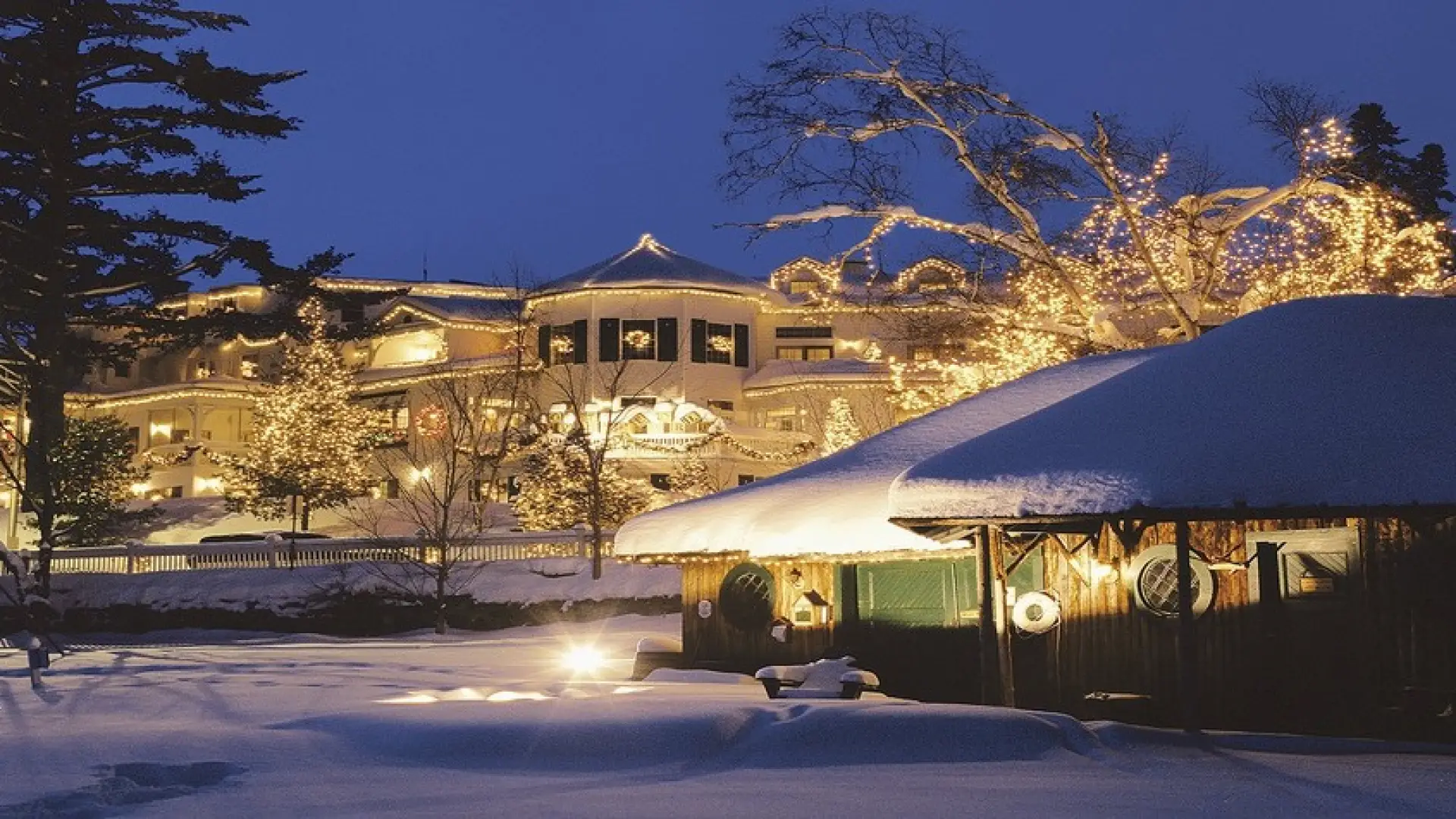 A winter scene of a vintage white hotel decorated for Christmas.