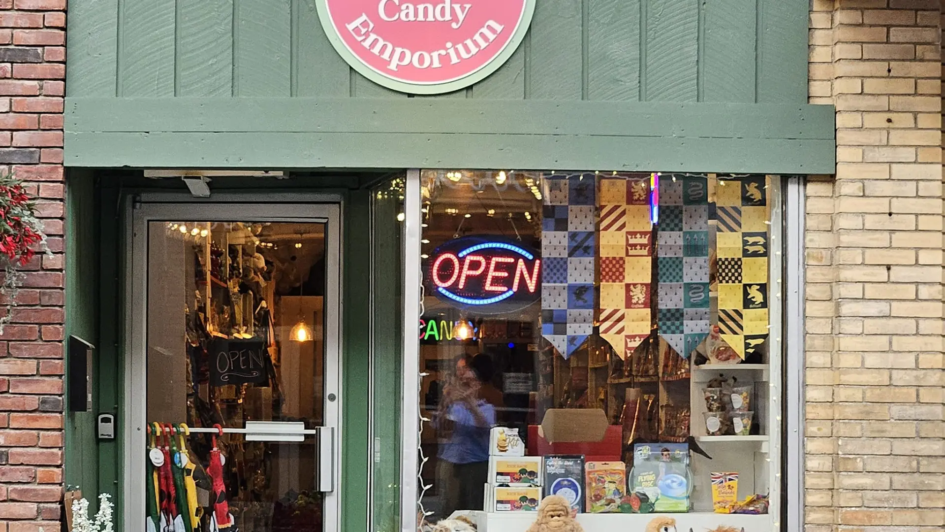 The exterior entry way of the candy emporium with green awning and pink circle emblem.