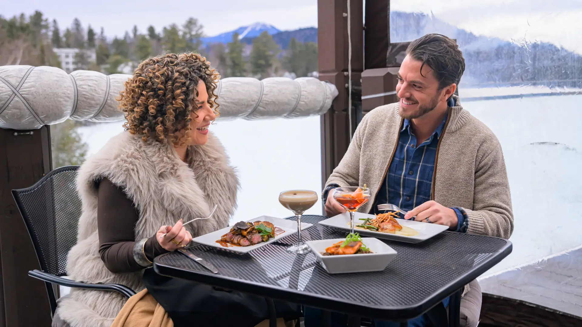 Man and woman dine on outdoor deck in winter