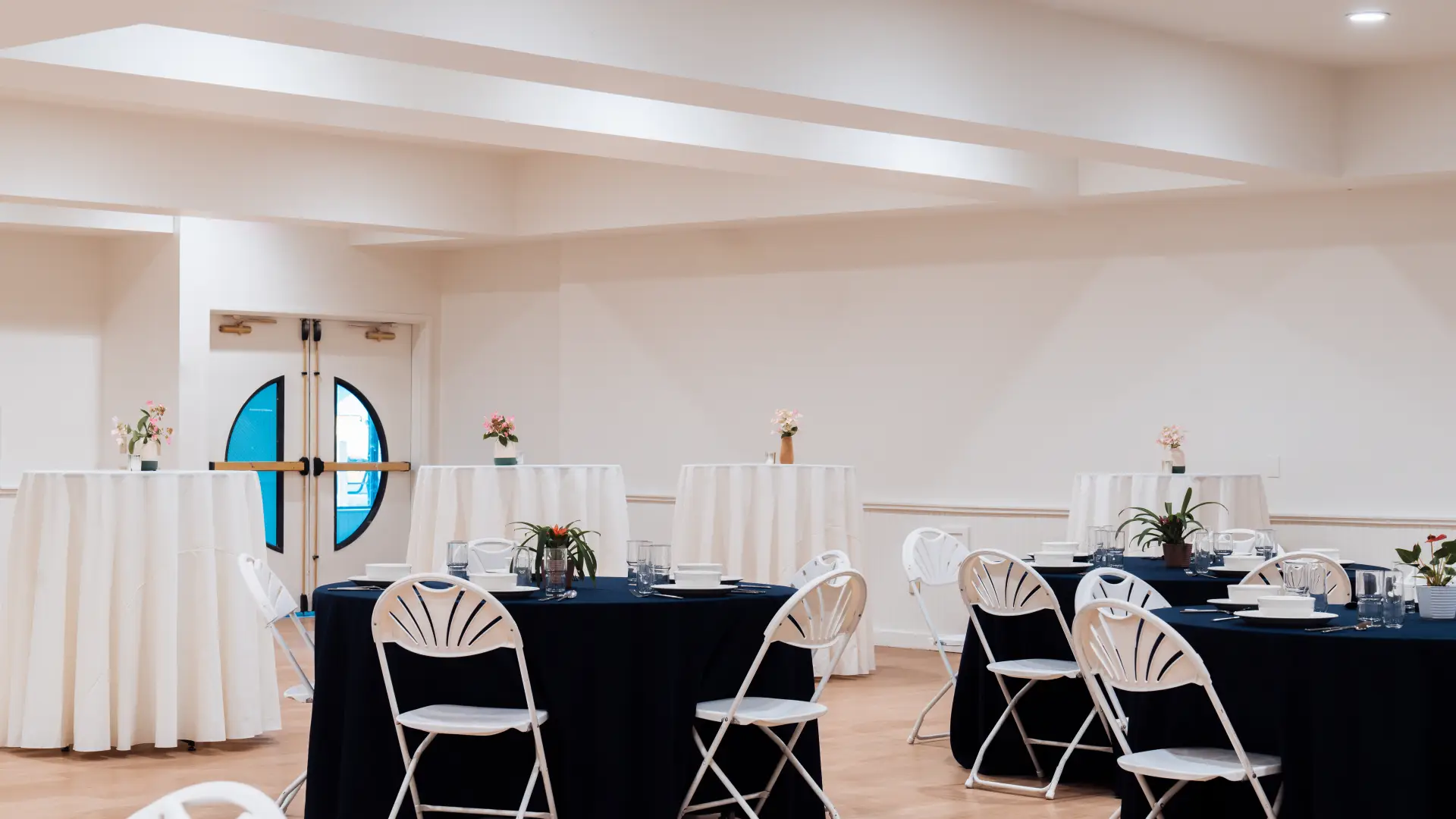 A bright white space with tables at seat height, ringed with bar height tables.