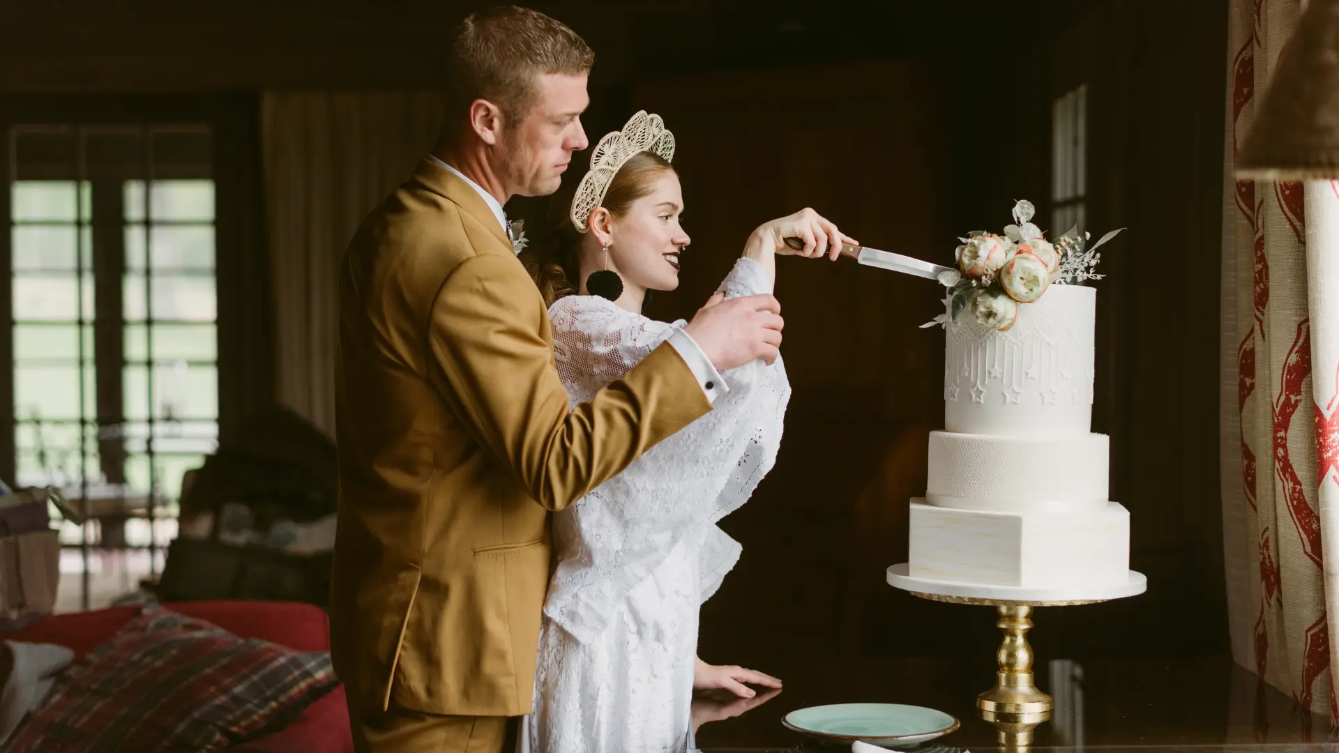 a bride and groom smile as they cut their wedding cake