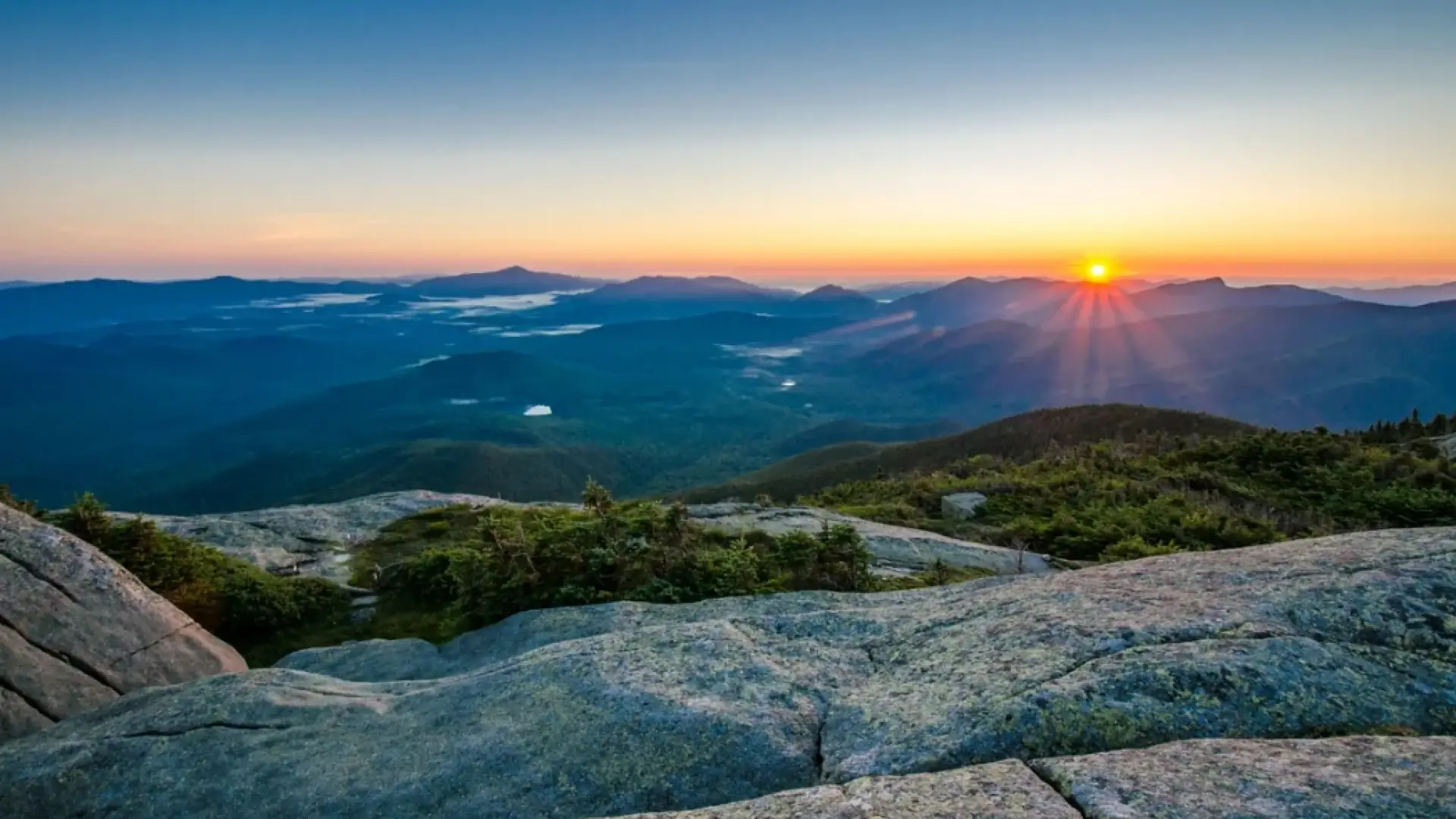 Sun rising over mountain range, seen from summit of another mountain