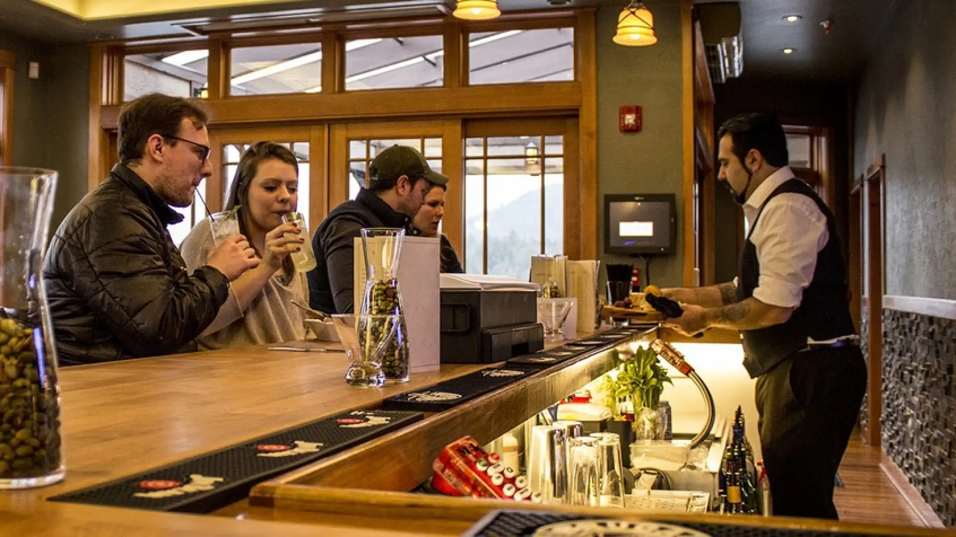 A bar tender serves patrons at a lodge-themed bar.