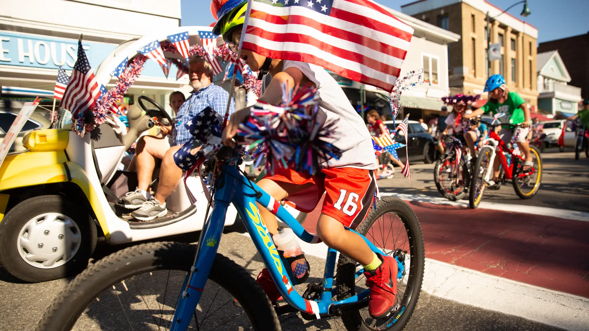 Kid rides bike with an American flag in the Lake Placid July 4th Parade