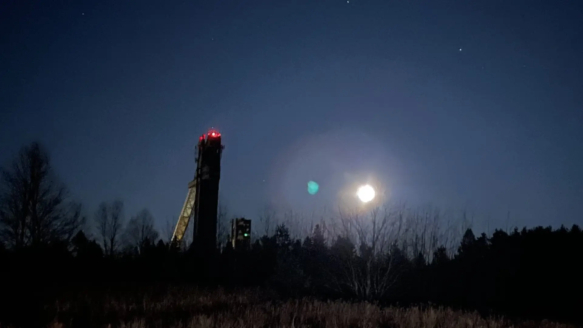 Full moon rising next to Olympic Ski Jumps at night