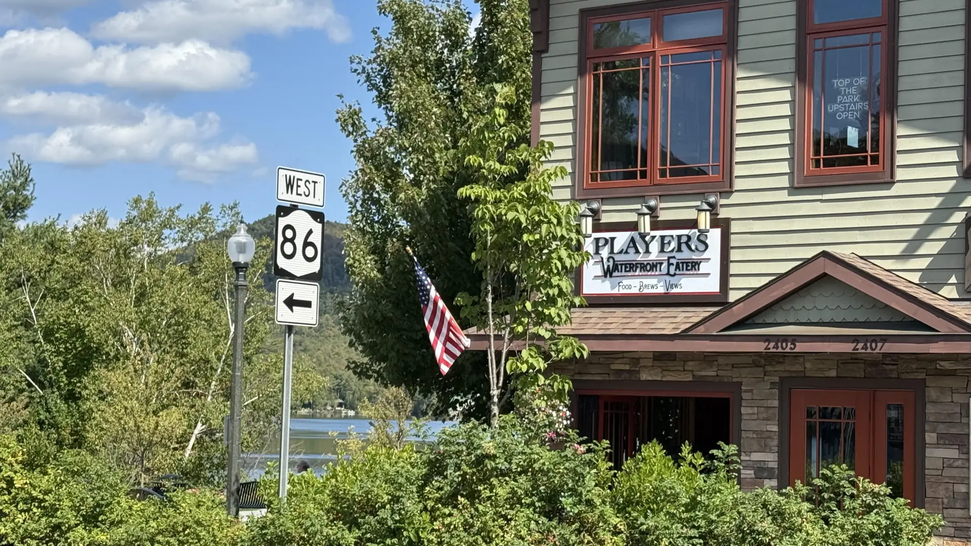 The exterior of Players Waterfront Eatery with Mirror Lake and the mountains in the background