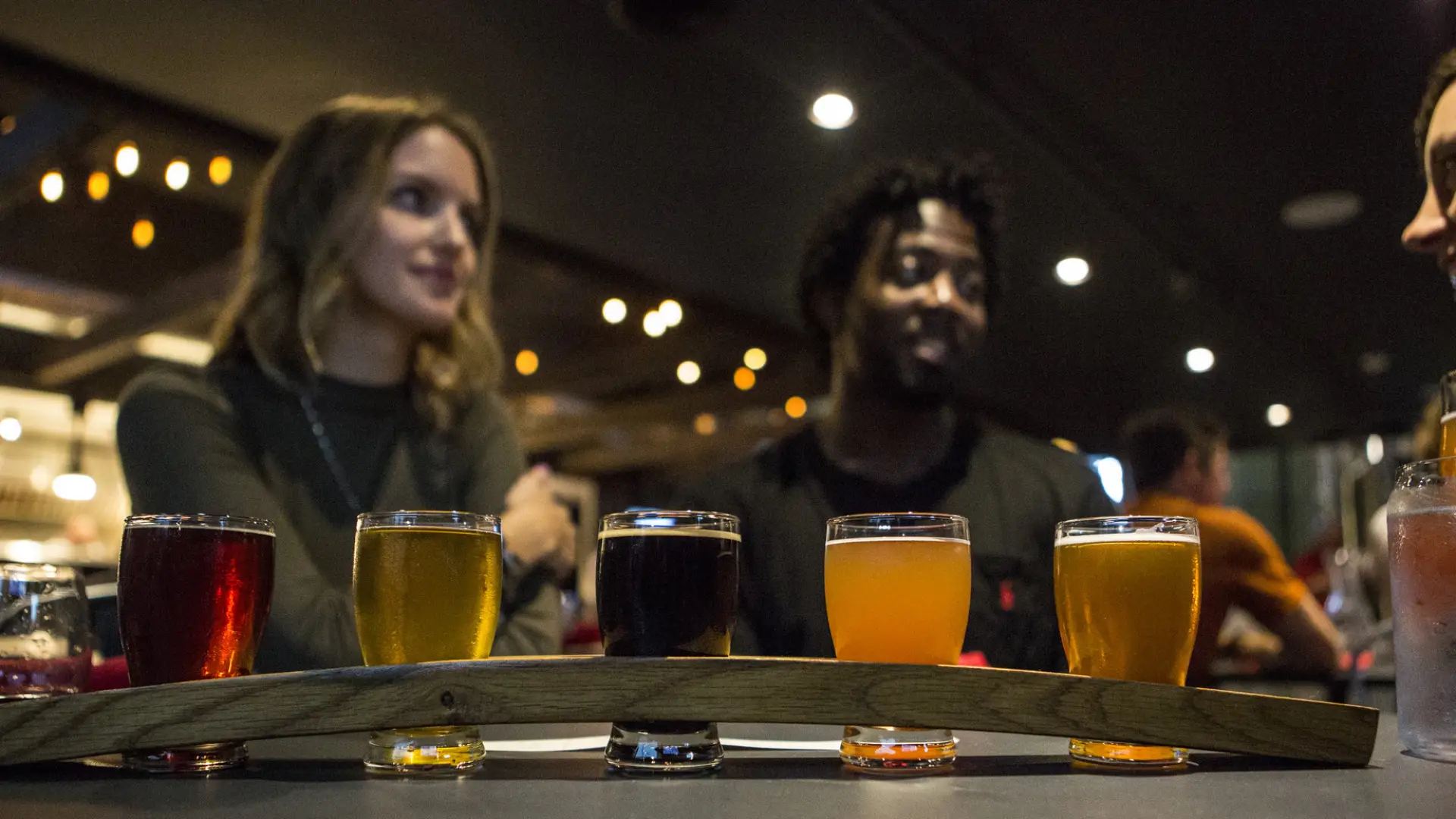 A flight of beer in front of a couple at Big Slide Brewery.