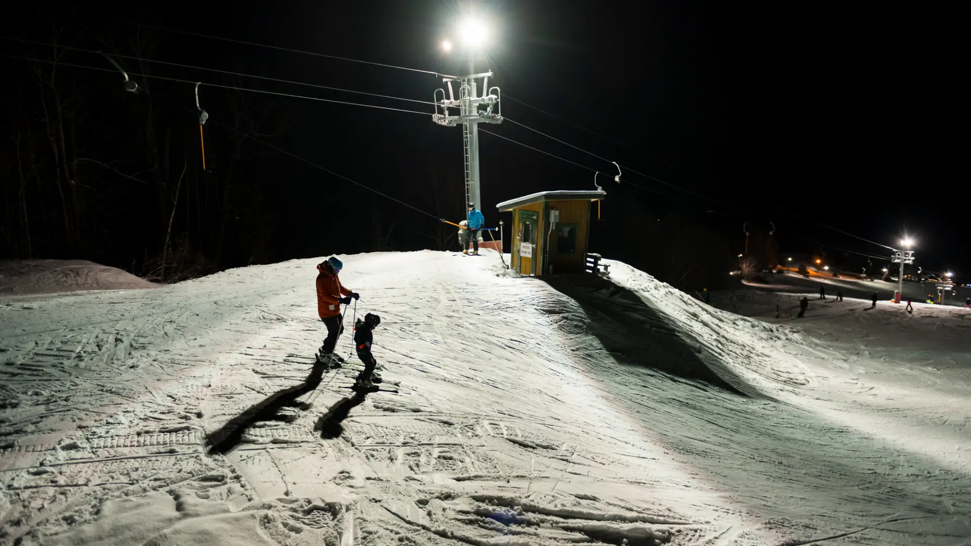 A couple people about to ski down during night skiing at Pisgah
