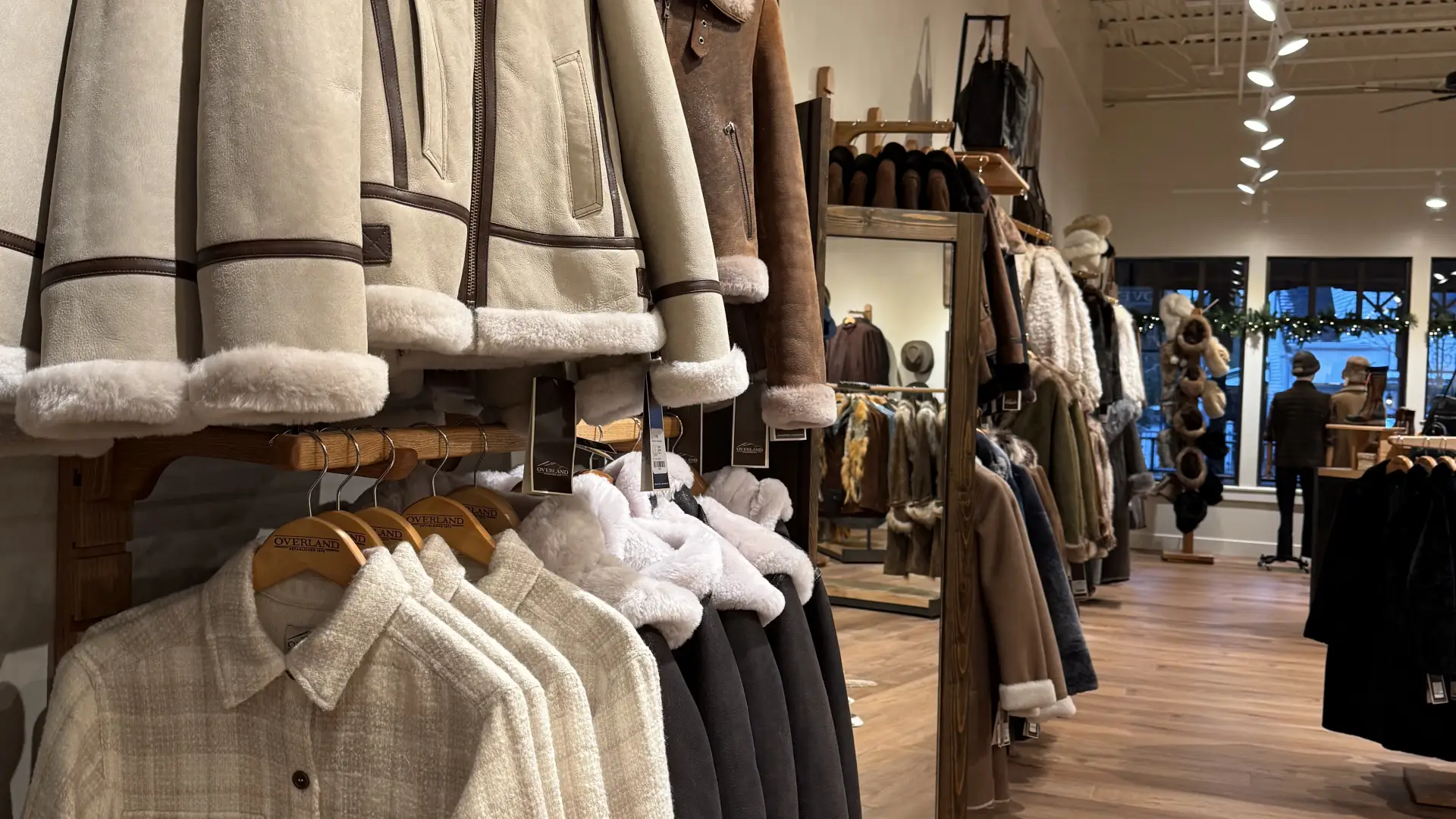 Coats on display in the deep storefront of Overland Lake Placid