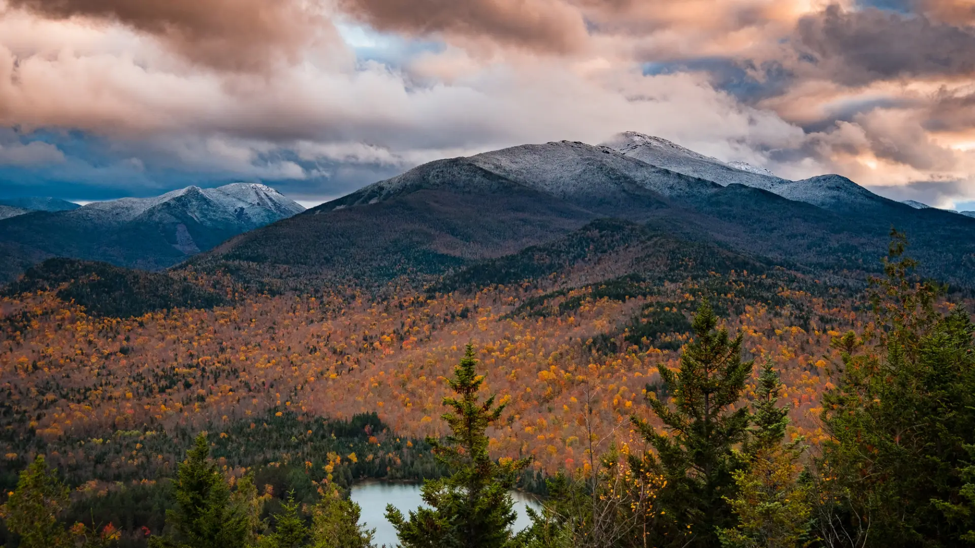 A pond and mountains with some snow on top during the late fall