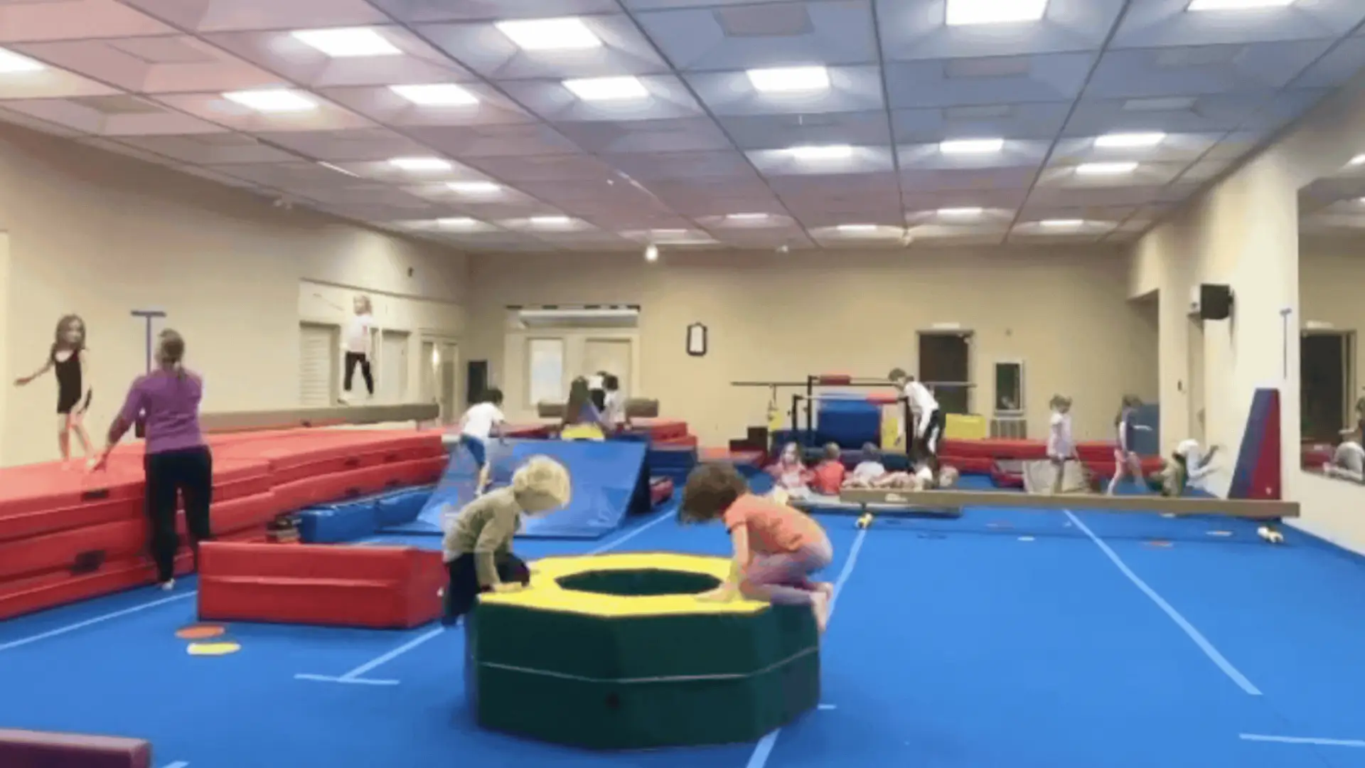 Room full of gymnastic mats and equipment and kids of varying ages practicing tumbling skills