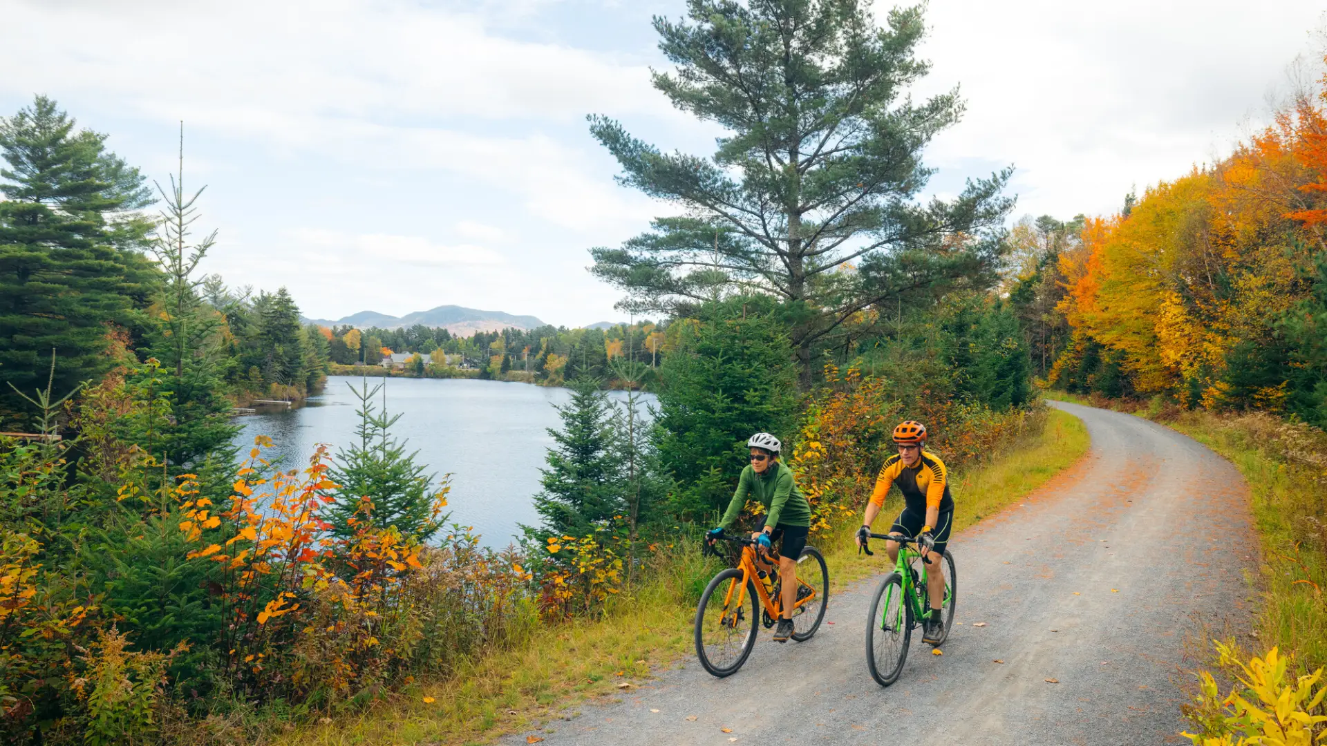 Two people cycle on a fall trail.