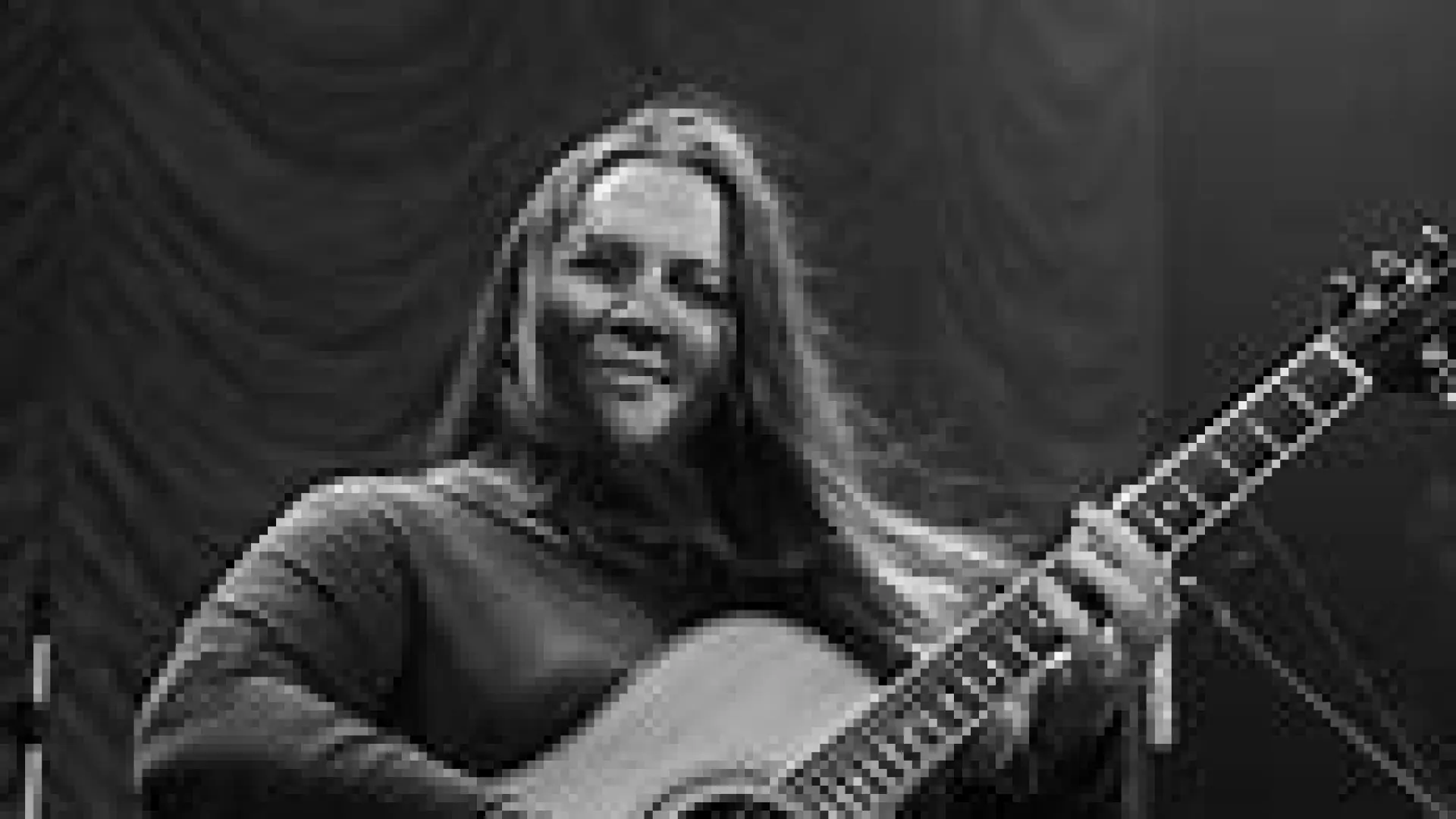 Black and white photo of a woman playing an acoustic guitar.