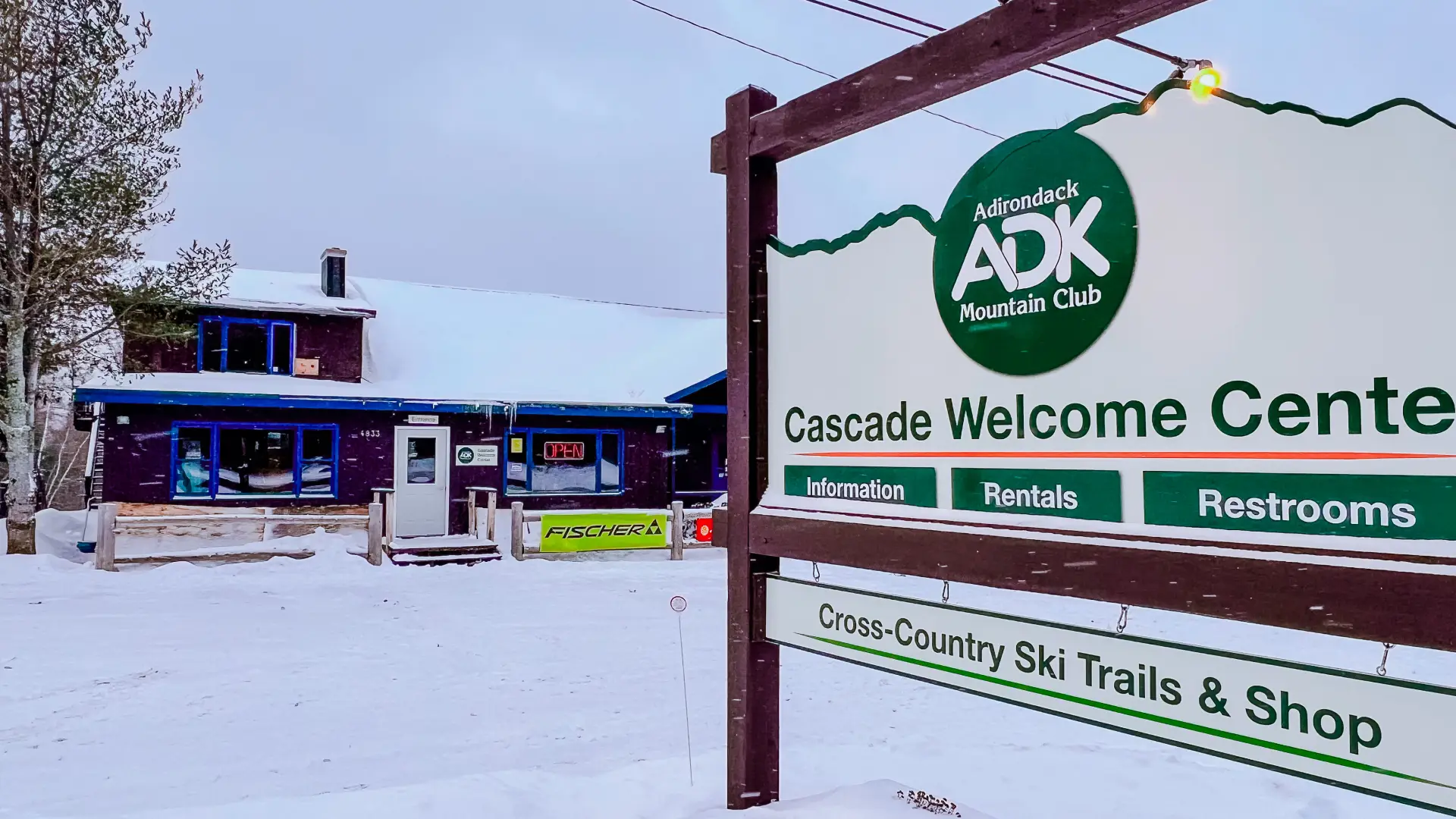 Cascade Welcome Center's sign in front of the snow-covered Adirondack Mountain Club building