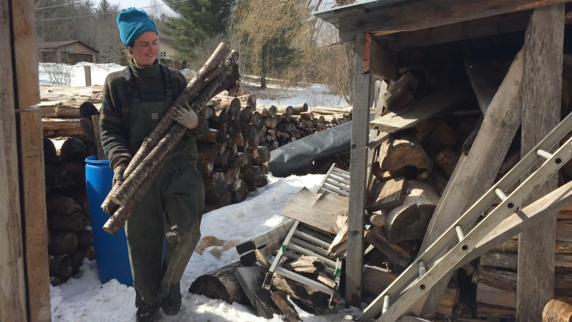 Lizzie, one of two assistants, is carrying wood for the wood fire stove beneath the evaporator.