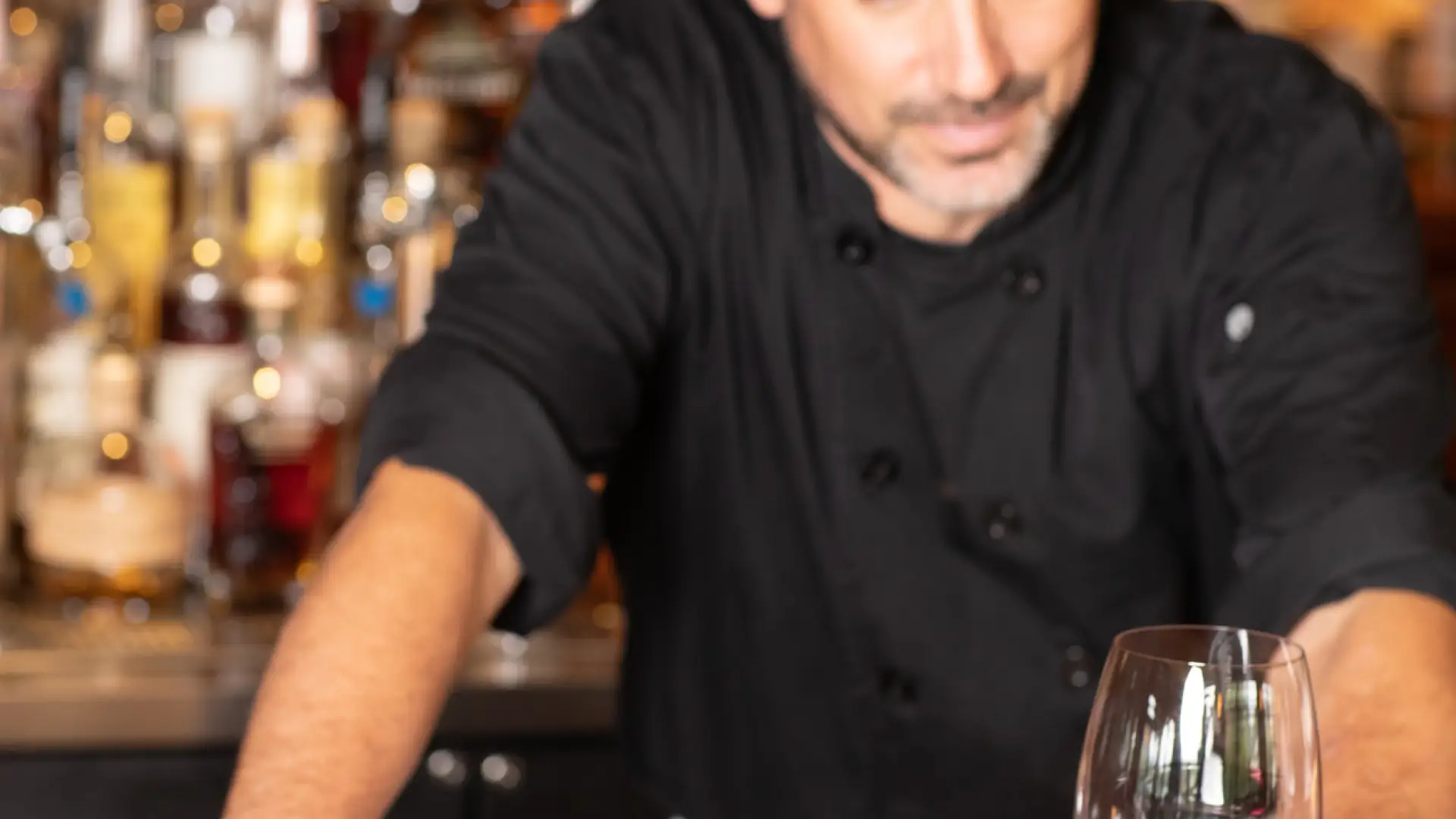 A man stands at a bar with tuna and a drink.