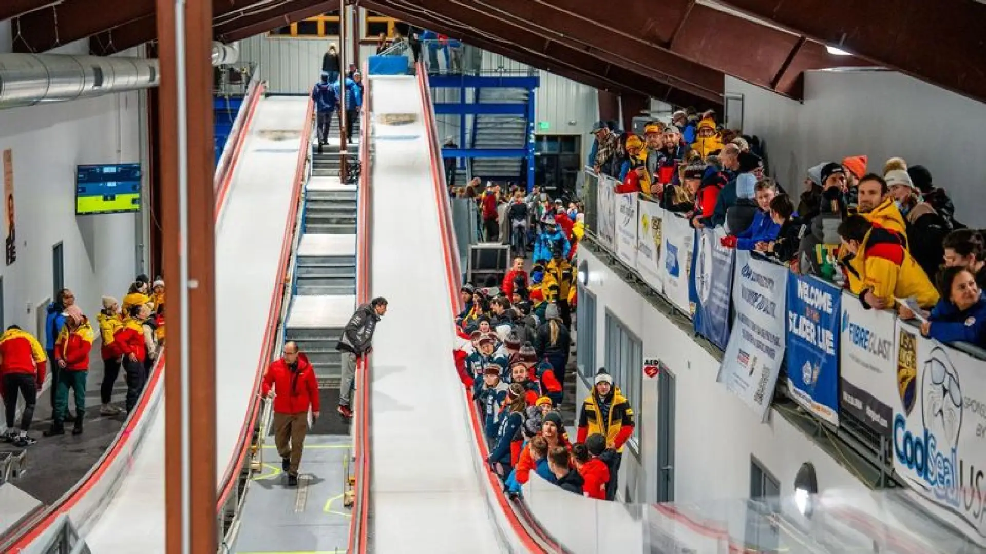 Indoor luge track with athletes and spectators.