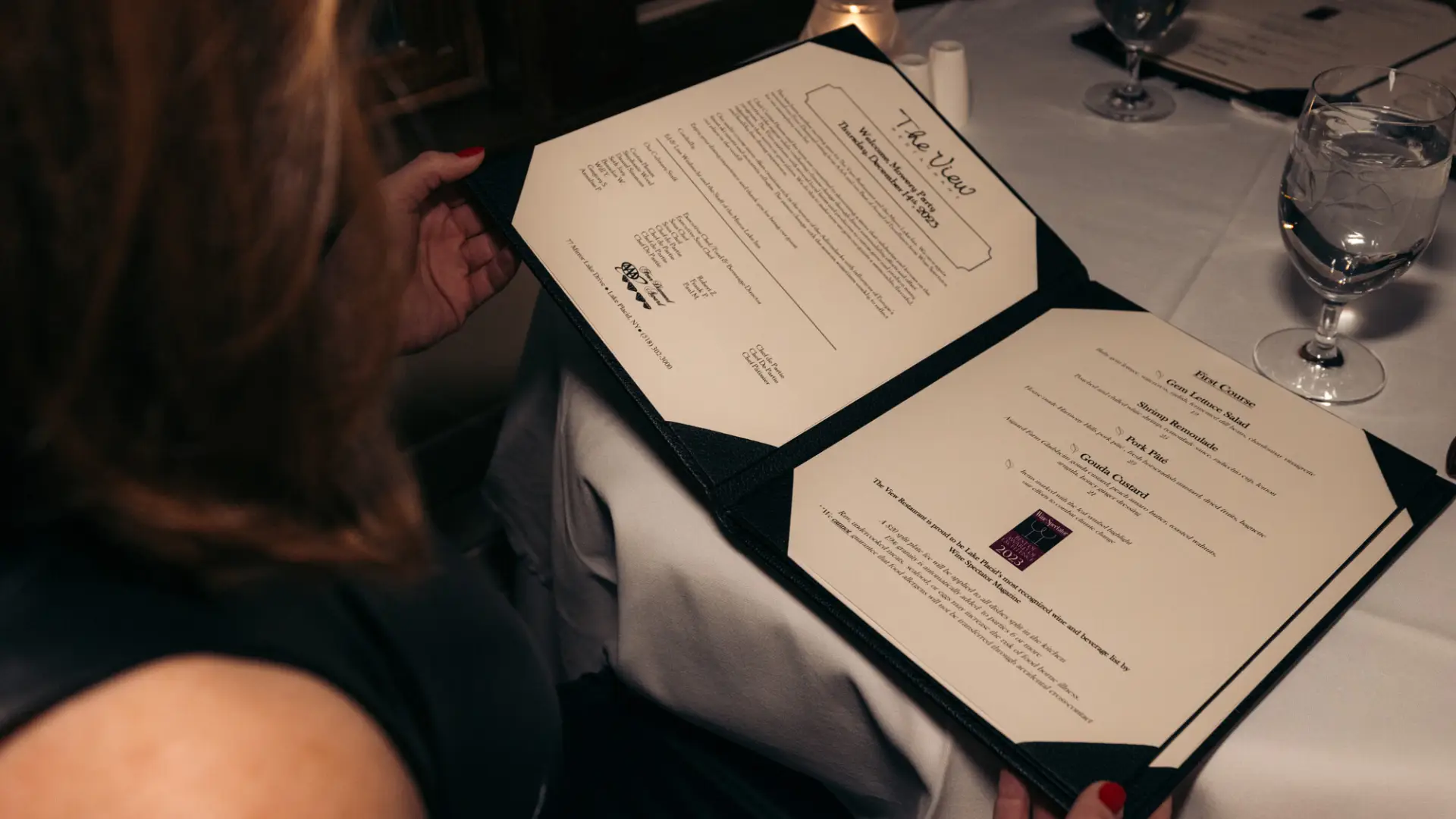A woman looks over a menu at a high end restaurant. 