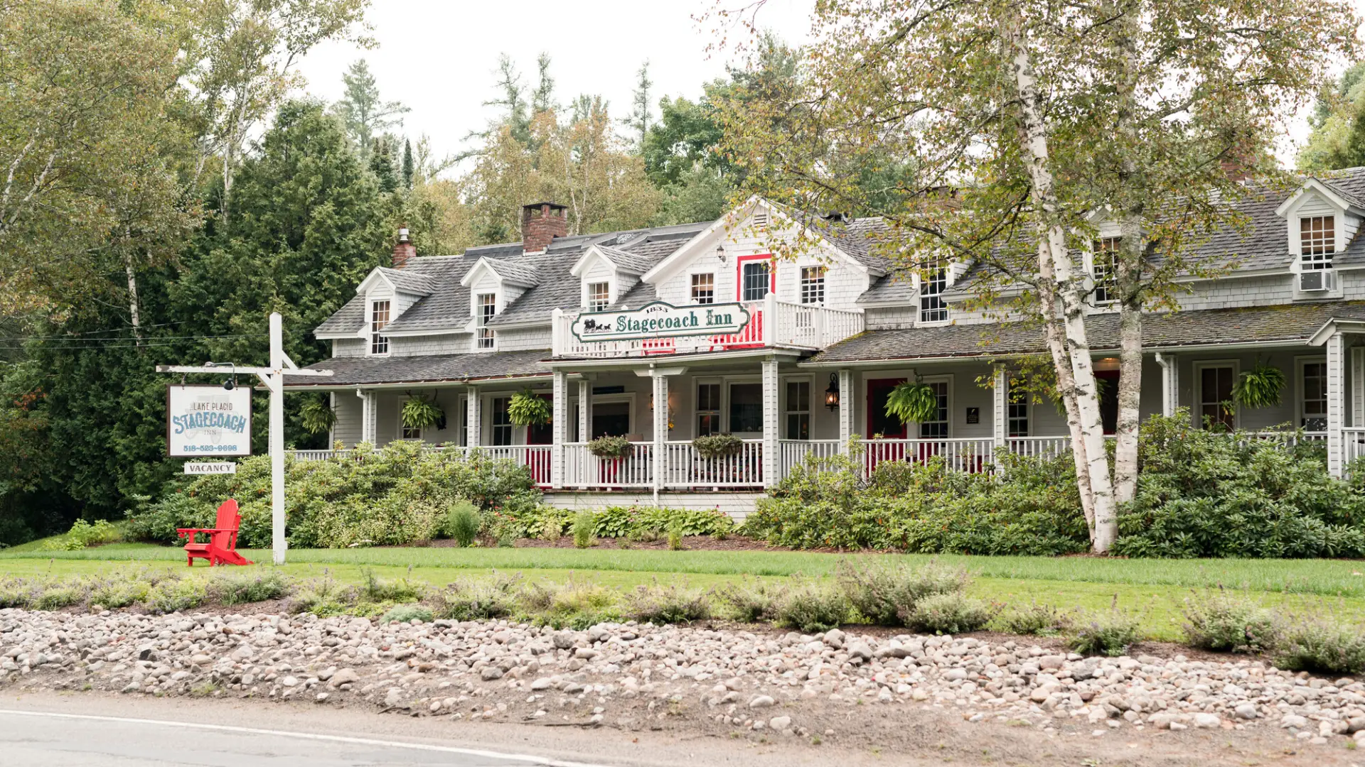 An white inn surrounded by an immaculate lawn.