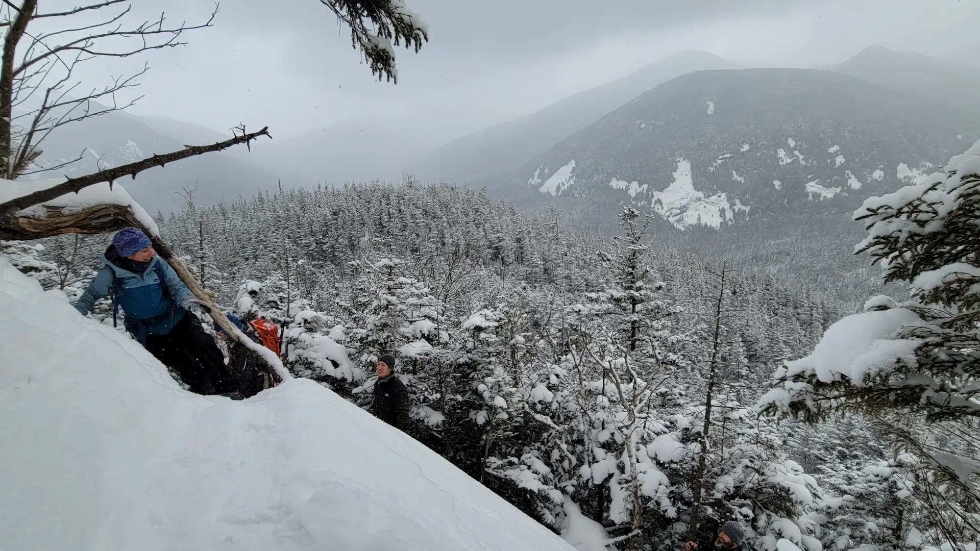 Winter hikers looking at a view from the top of a snowy cliff