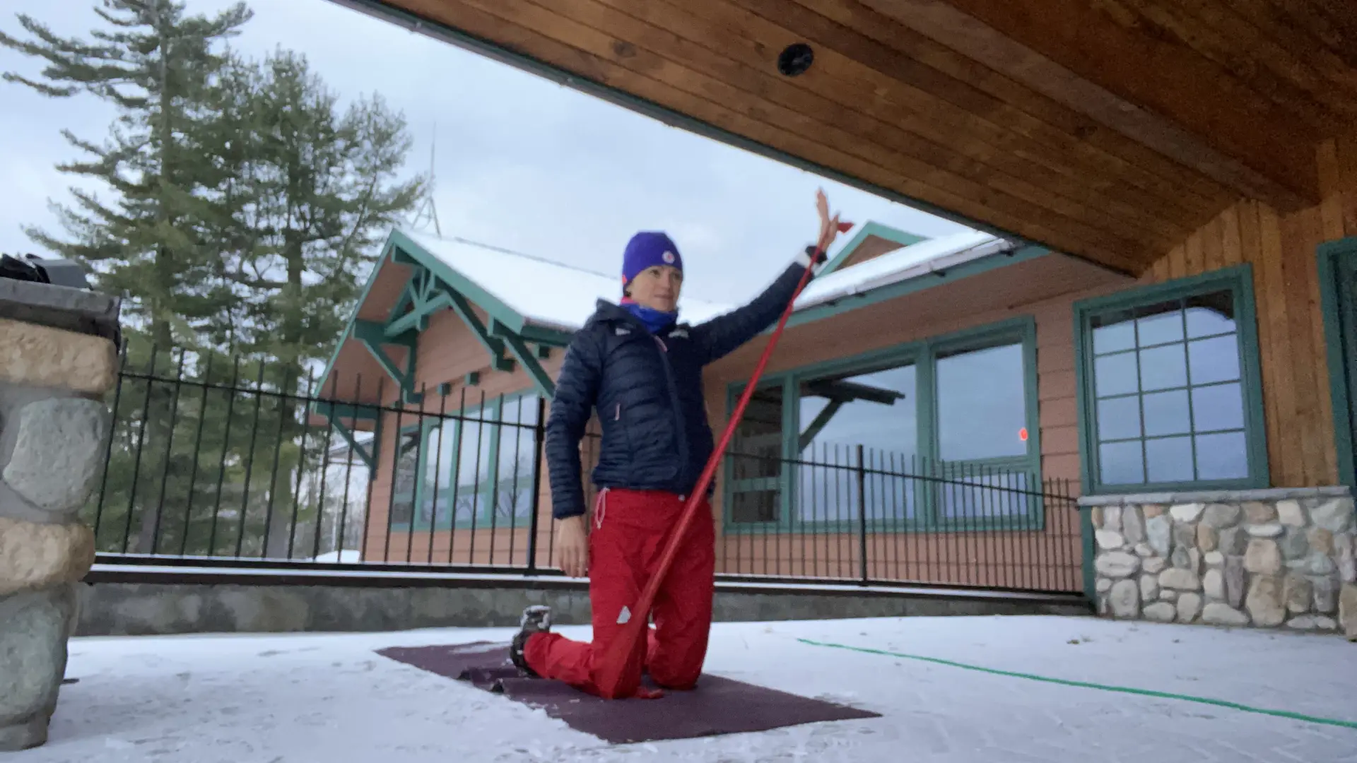 Person upside down doing yoga on a snowy deck outside a building.