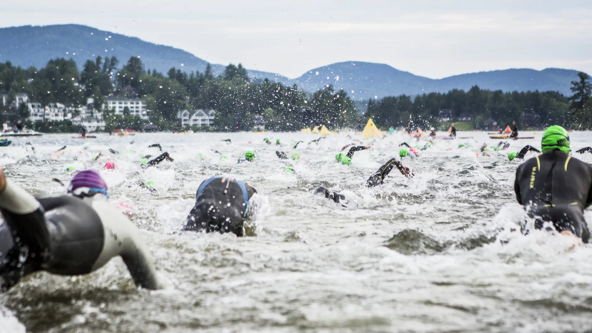 A group of swimmers splashes in the water of Mirror Lake on the morning of the Ironman Race in Lake Placid