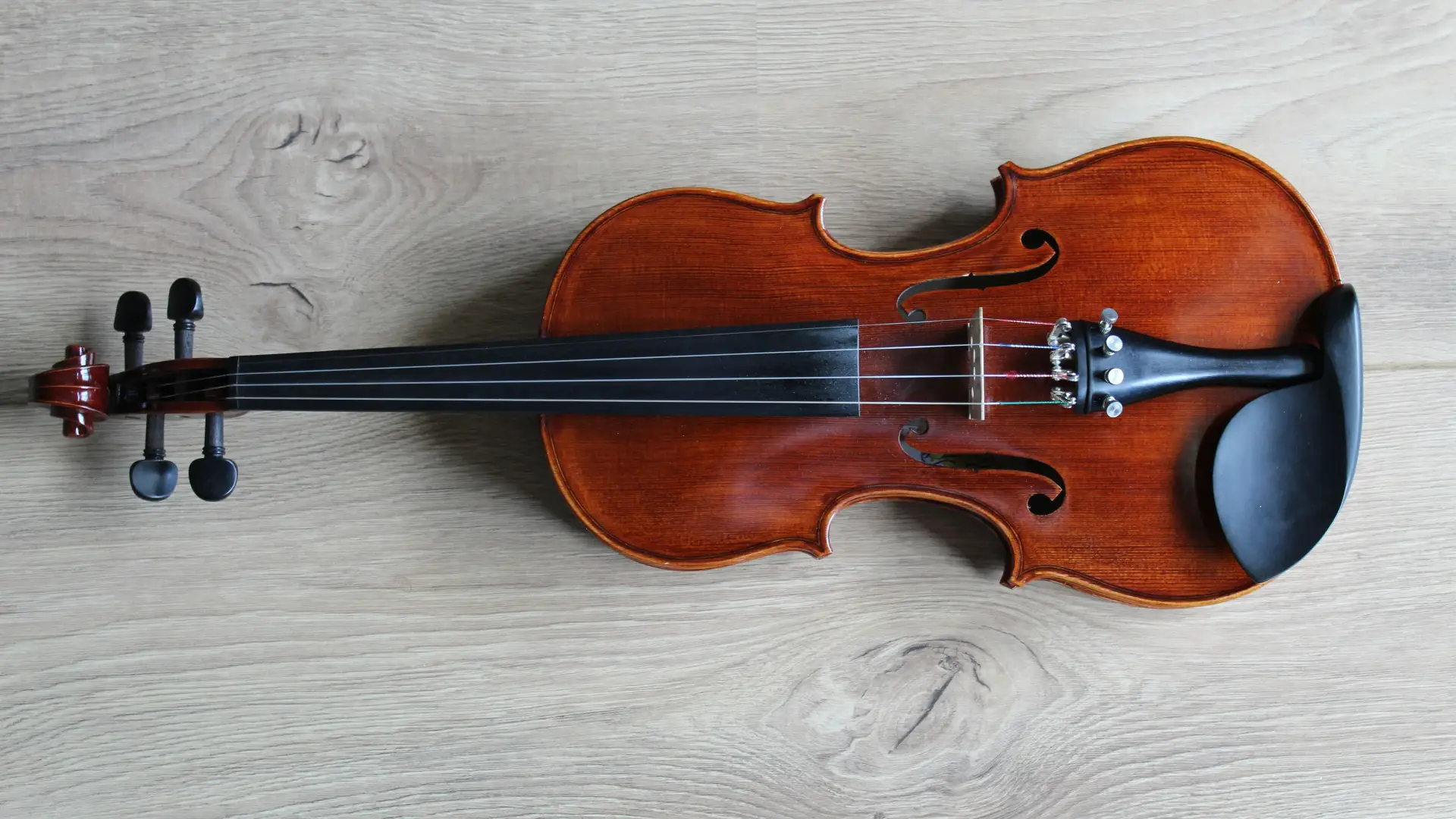 Stock image of a violin laying horizontally on a white wooden background