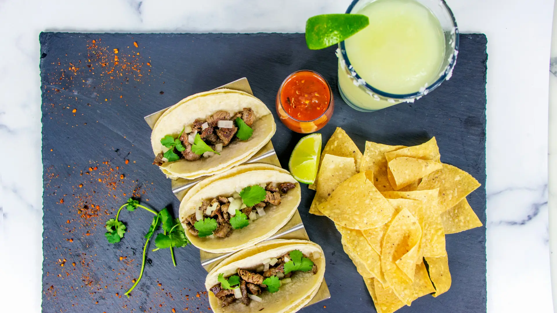 Overhead view of slate board holding tacos and margarita