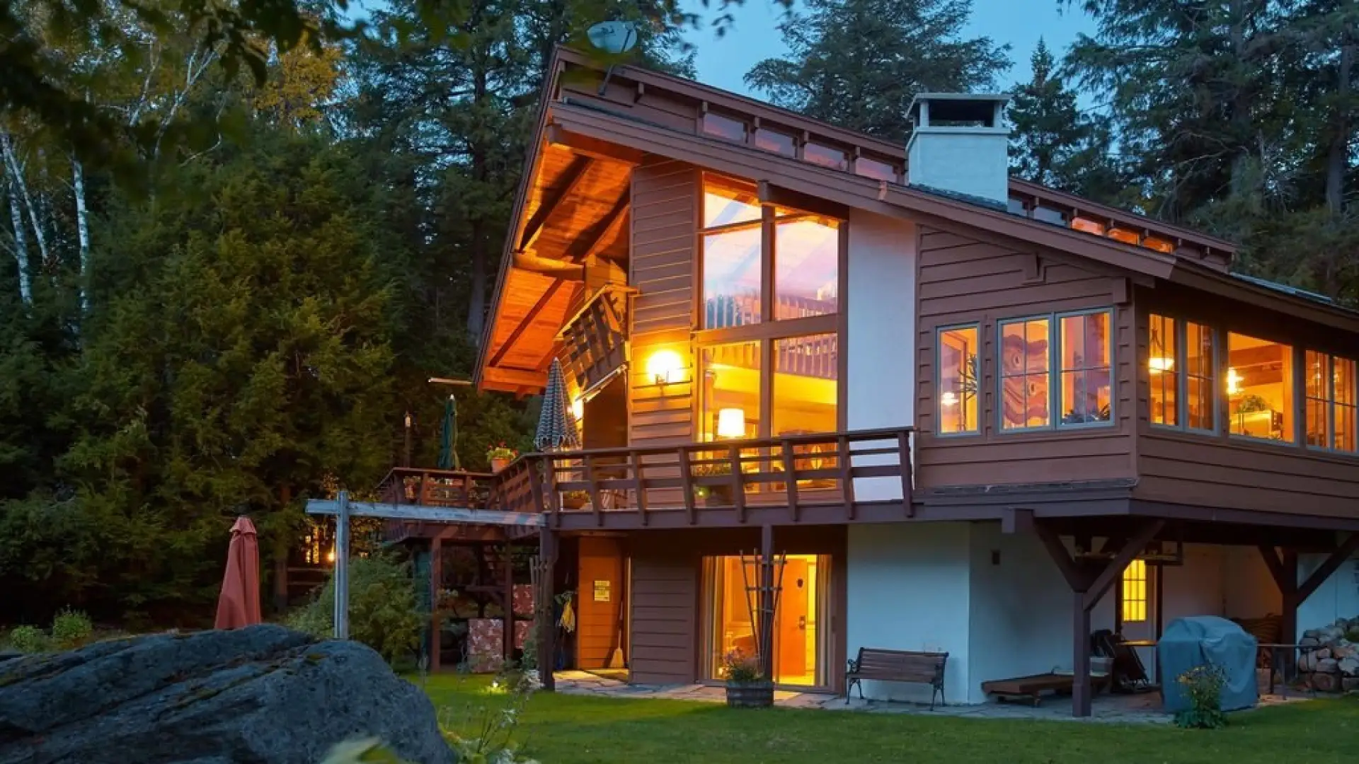 A large and warmly illuminated log cabin in the woods.
