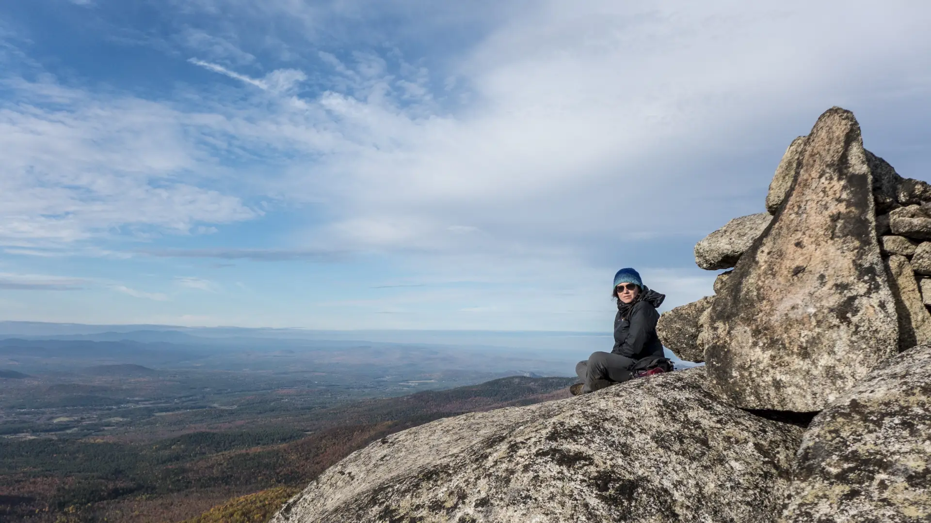 A hiker sits on the rocks on a summit