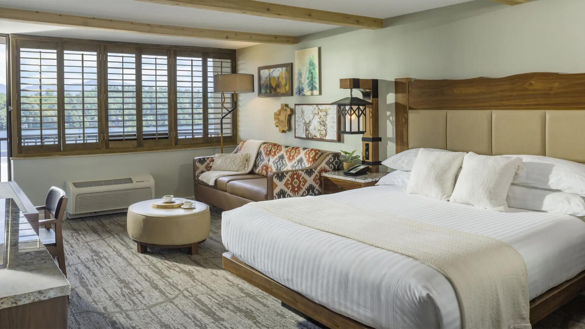 Large bed next to sitting area next to window with wooden blinds