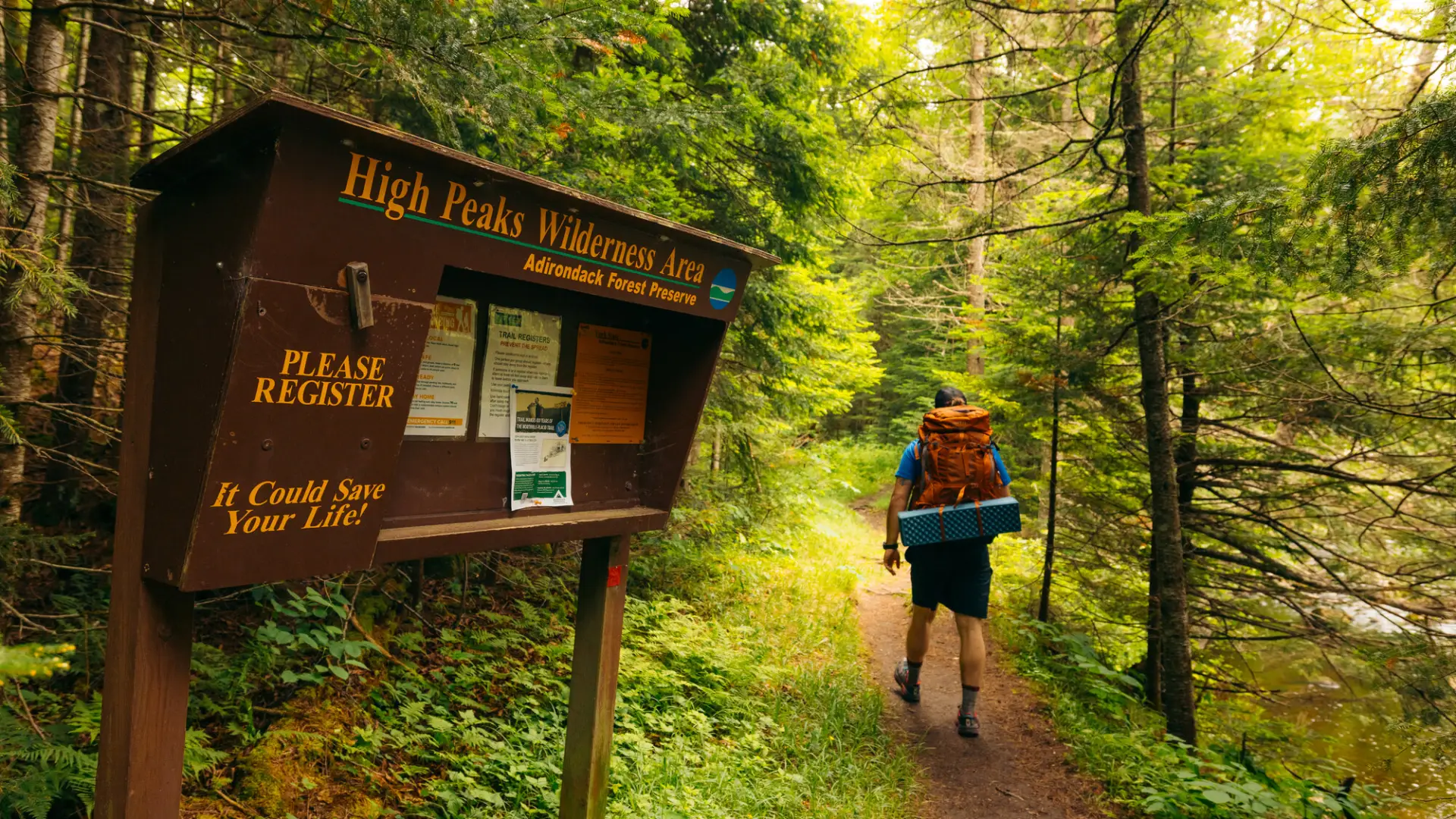 A hiker walking into the woods from a register box