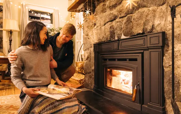 A couple sits in front of a fireplace during their stay in Lake Placid.