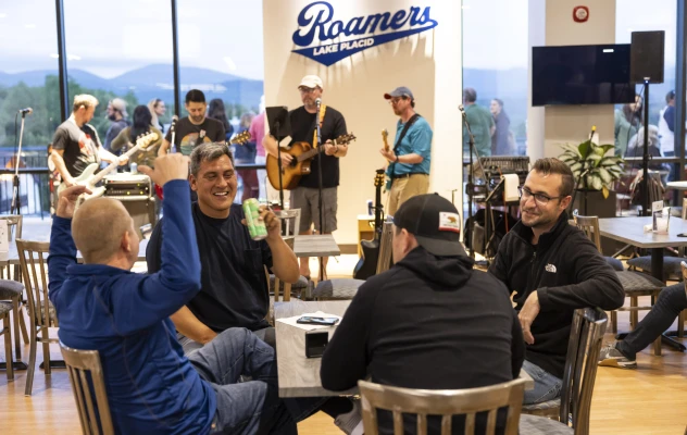 A group of men sit at a table while a band plays in the background.