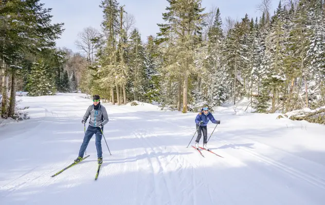 Two people cross-country skiing on a trail.