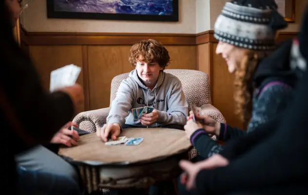 Family in winter clothing plays cards at small table
