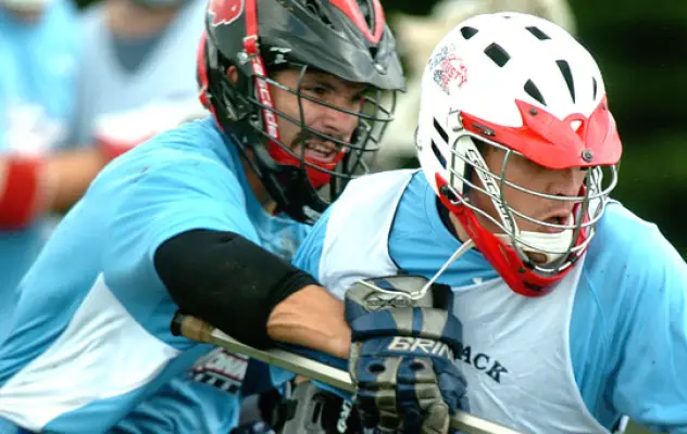 Two men play lacrosse and fight over a ball.