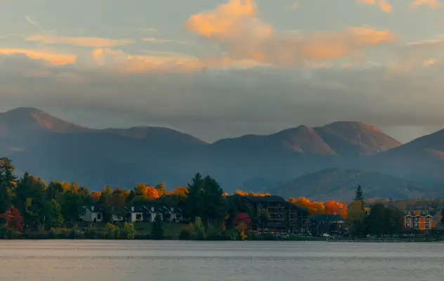 A lakeside resort with mountains in the background covered in fall foliage. 