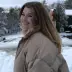 A woman smiles at the camera in a snowy image. 