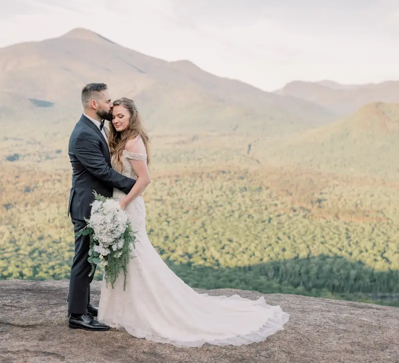 Bride and Groom embrace atop a mountain vista