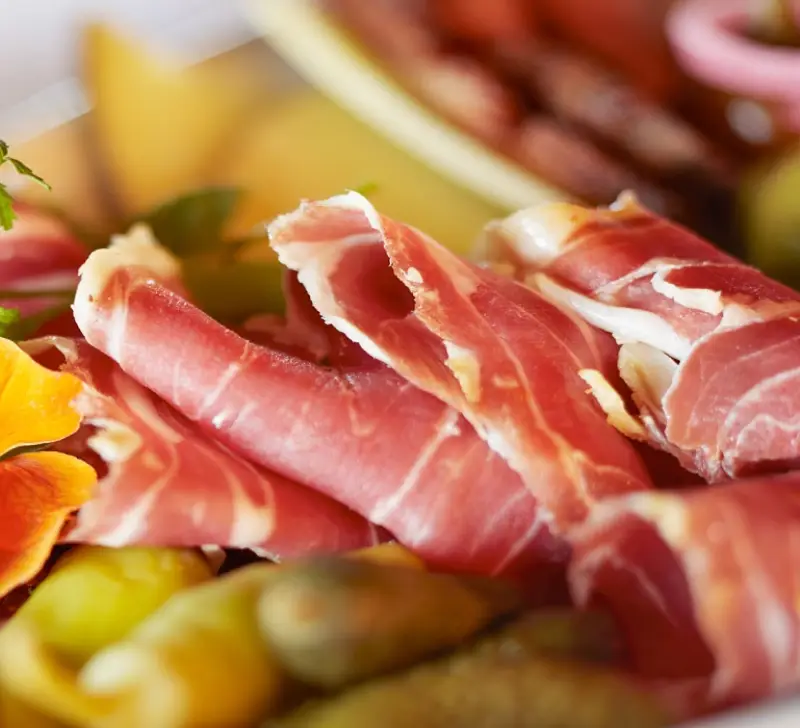Delectable meats and cheeses on a plate.