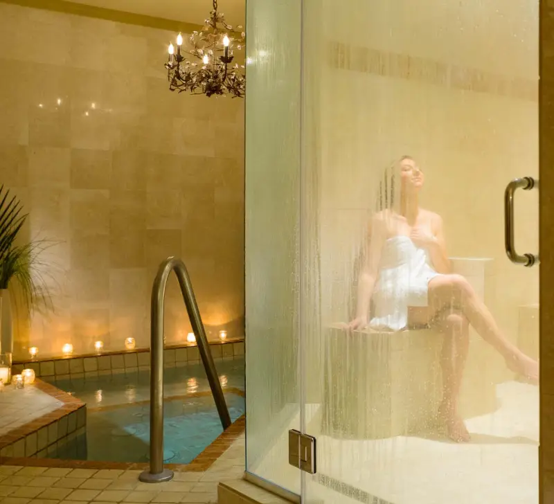 A woman sits wrapped in a lush towel while basking in the rejuvenating steam room.