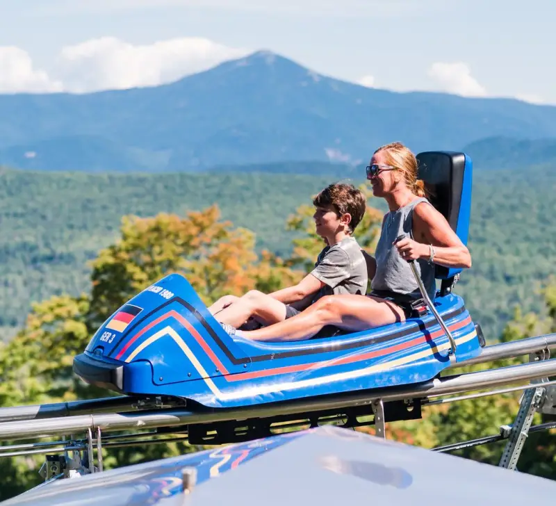 A woman and her young son ride a mountain coaster.
