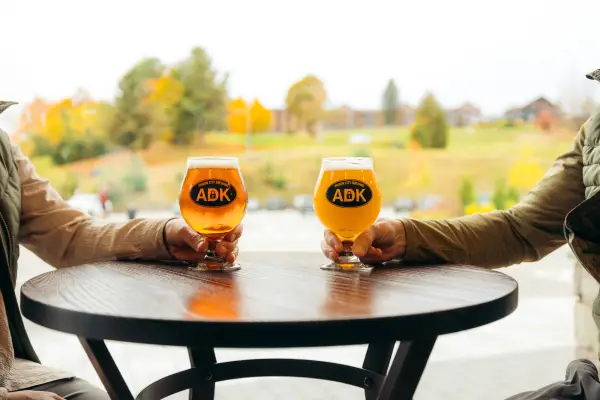 Craft beer on a table with fall scenery in the background.