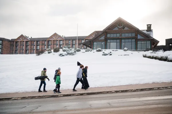 A family walks up to a hotel in the snow.