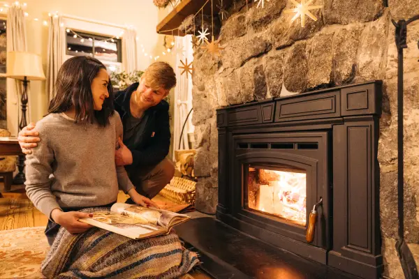 A man and woman sit by a fireplace. 