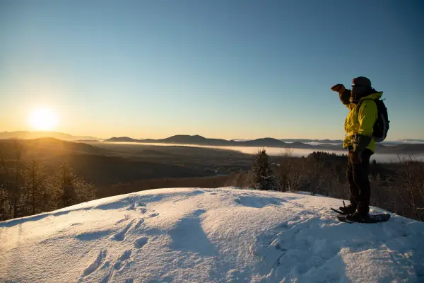 A snowshoer on a small bald summit