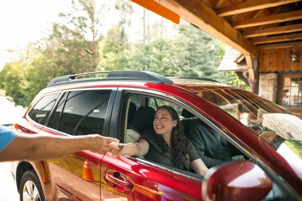 A woman grabs a brochure from an attendant in her car. 